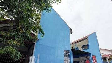 A blue building with a gated entrance, a motorcycle parked in front, and a tree partially obscuring the view.