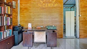 A reception desk with a wooden backdrop, a bookshelf, and a vintage radio. - OYO 90474 Caravan Camp (Batu)