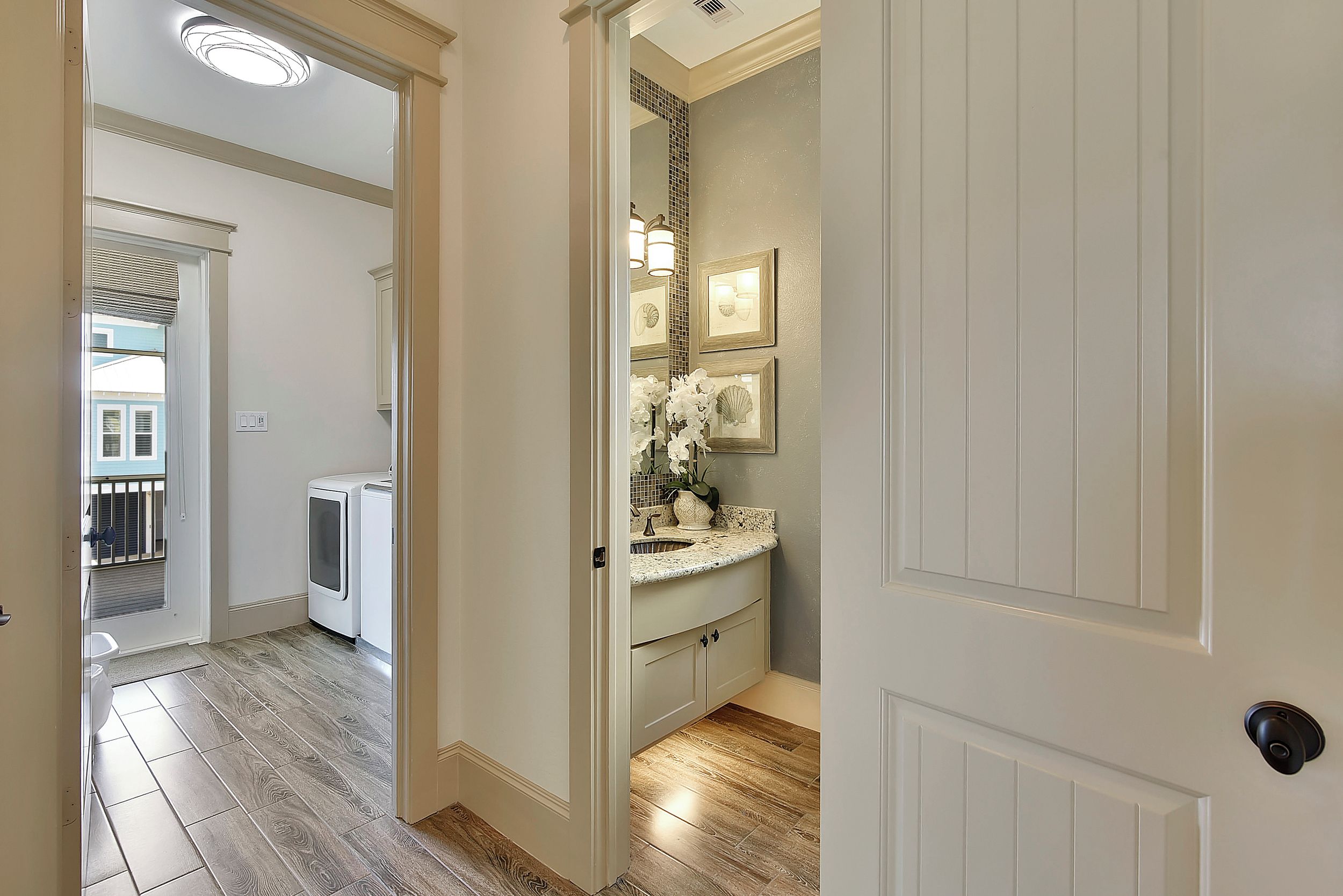 A bathroom with a sink, mirror, and vanity. There is a door leading to another room.