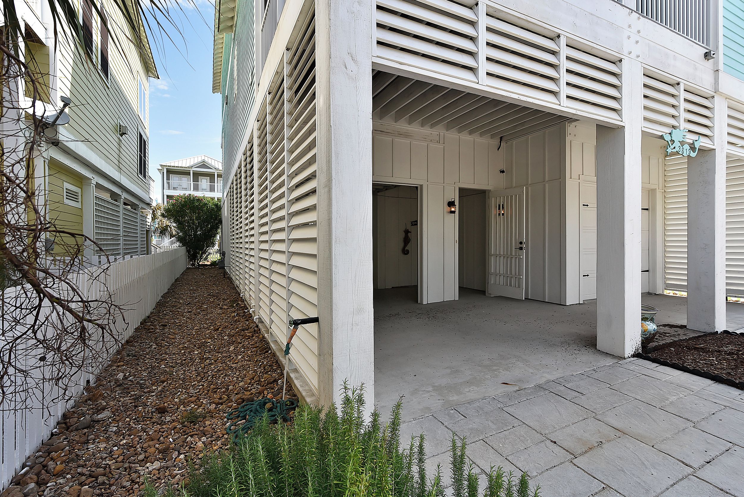 Ein schmaler Pfad führt zu einem Gebäude mit einem überdachten Eingang und einer sichtbaren Tür.