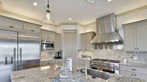 Uma cozinha moderna com eletrodomésticos de aço inoxidável, bancadas de granito e uma ilha central.