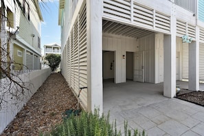 A narrow pathway leading to a building with a covered entrance and a visible door. - Neptune's Sanctuary by Ryson Vacation Rentals (Galveston)