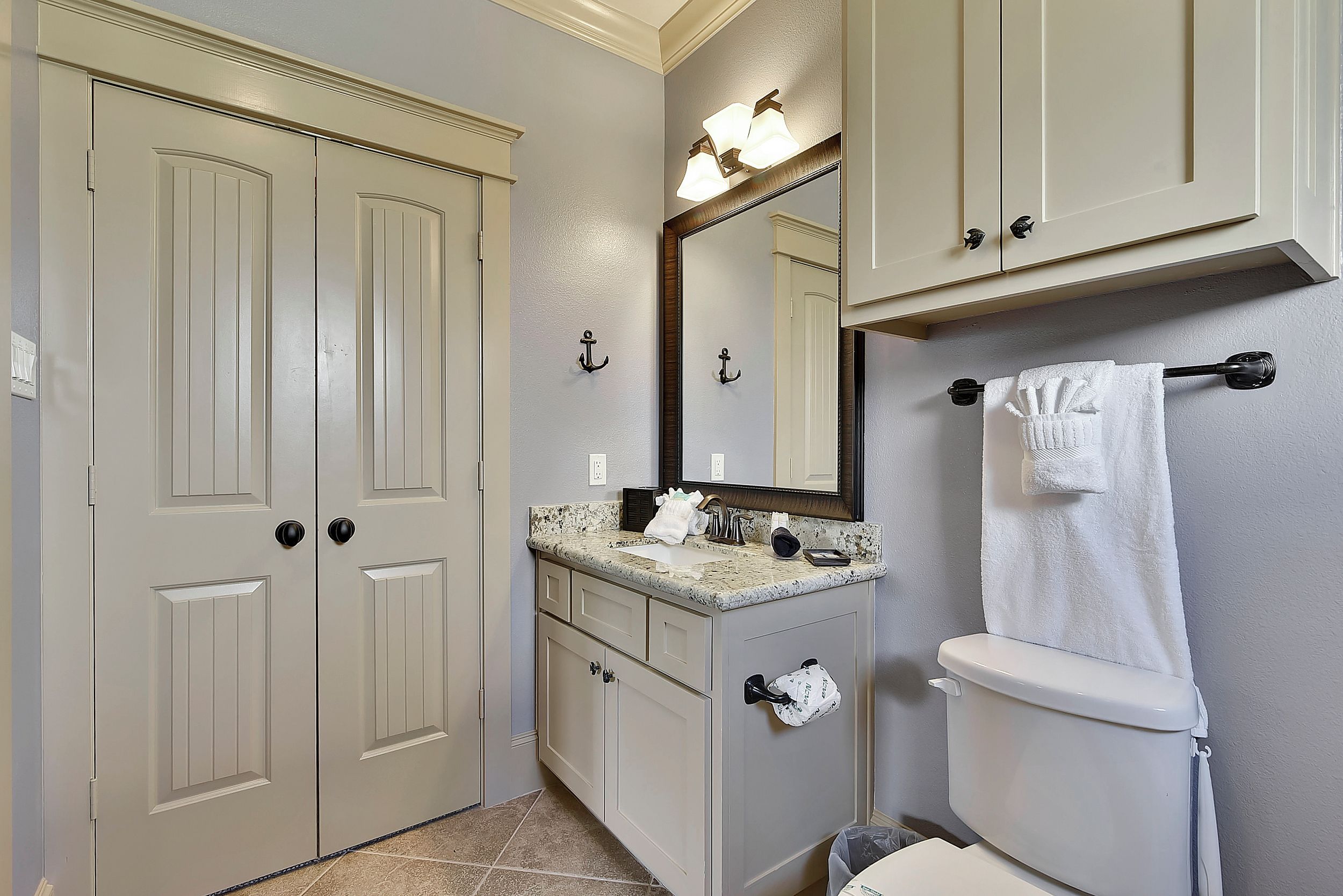 A bathroom with a double vanity, a toilet, and a large mirror.
