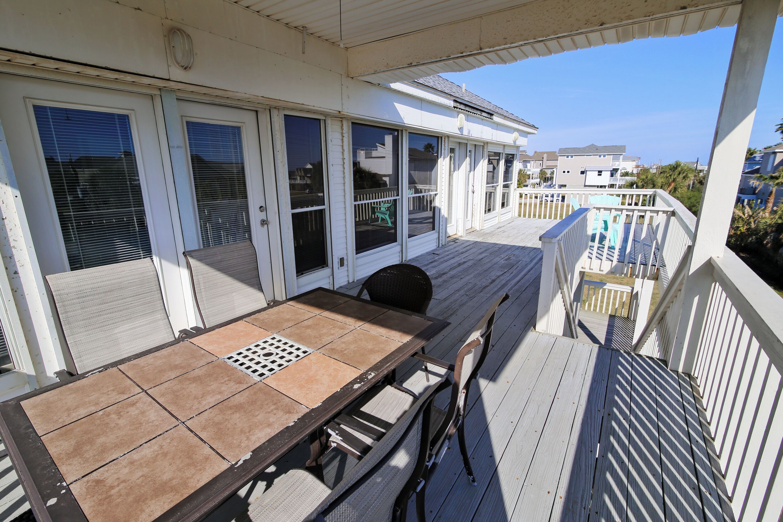 A covered outdoor area with a wooden deck, a table with chairs, and a view of the surrounding buildings.