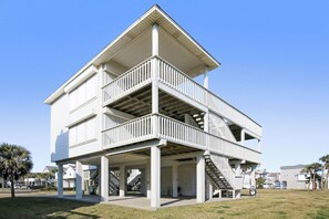 Ein mehrstöckiges Gebäude mit einem Balkon im zweiten Stock, einem überdachten Bereich im Erdgeschoss und einer Treppe, die die Etagen miteinander verbindet.
