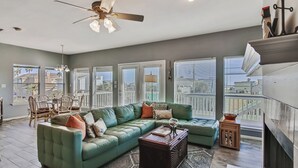 A spacious living room with a green sectional sofa, a wooden coffee table, and a fireplace.