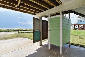 A covered outdoor area with a concrete floor, a wooden deck, and a view of the beach.