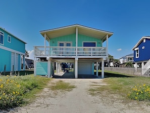 A two-story house with a balcony, a covered porch, and a garage. - Paradise Found by Ryson Vacation Rentals (Galveston)
