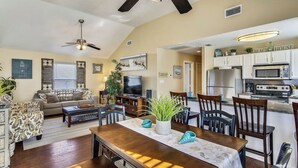 A spacious living room with a dining area, a kitchen, and a ceiling fan. - Pirates' Treasure by Ryson Vacation Rentals (Galveston)