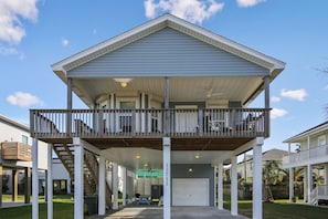 Une maison à deux étages avec un balcon, un garage et une véranda couverte.