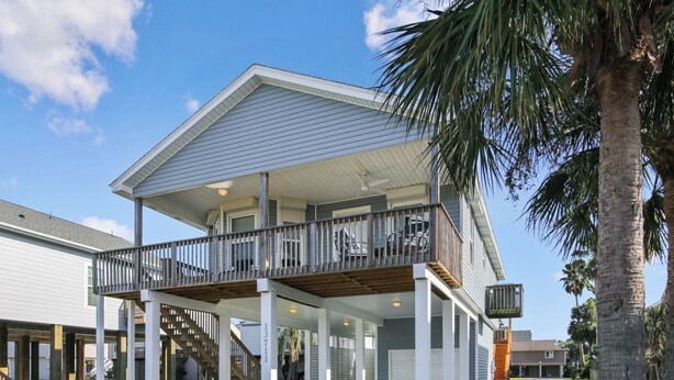 A two-story house with a covered porch and a balcony. - Pirates' Treasure by Ryson Vacation Rentals (Galveston)