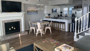 A modern kitchen with white cabinets, a stainless steel refrigerator, and a dining area with a round table and chairs.