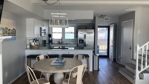 A modern kitchen with a central island, white cabinetry, and a dining area with a round table and chairs.
