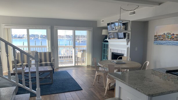 A modern kitchen with a dining area, a staircase, and a view of the marina.