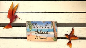 Un letrero con una escena de playa tropical y el texto 'We're On Island Time!'