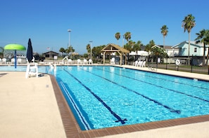 A swimming pool with clear blue water, surrounded by lounge chairs and a gazebo.