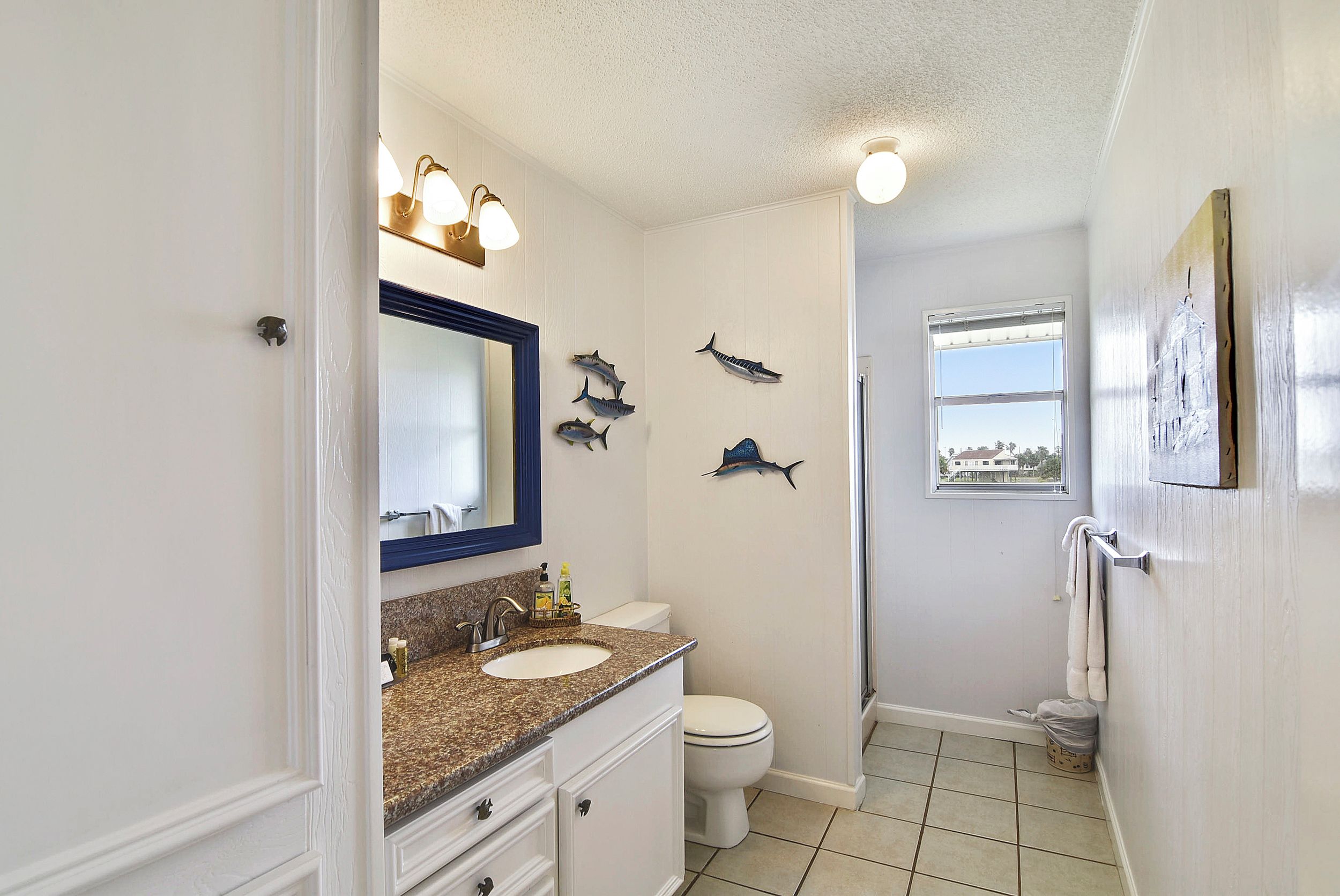 Une salle de bain avec un meuble-lavabo blanc, un évier, des toilettes et un espace douche.