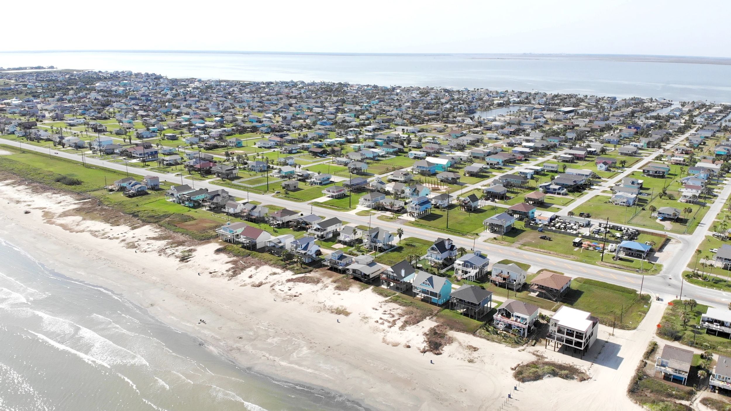 Vista aérea de una zona residencial costera con casas, carreteras y una playa.