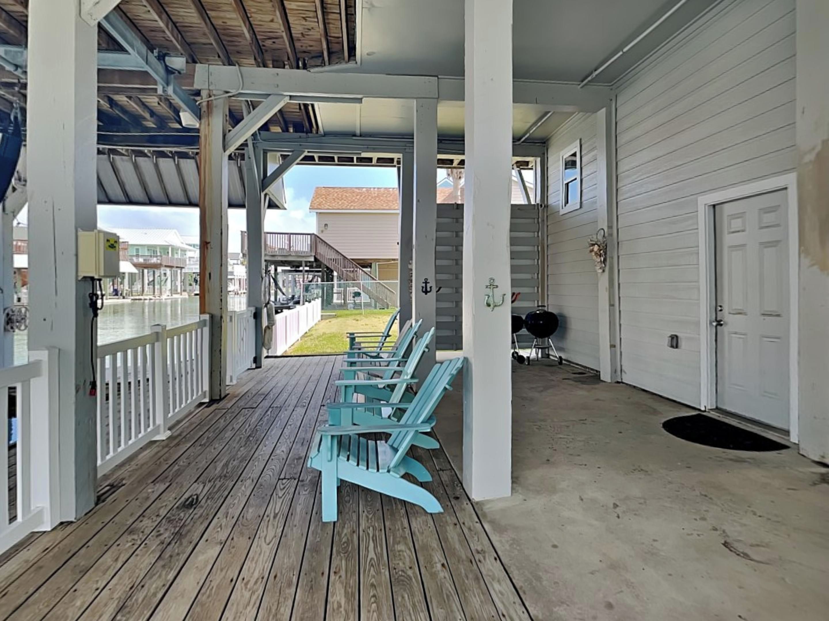 Un portico coperto con pavimento in legno e poltrone Adirondack azzurro chiaro.