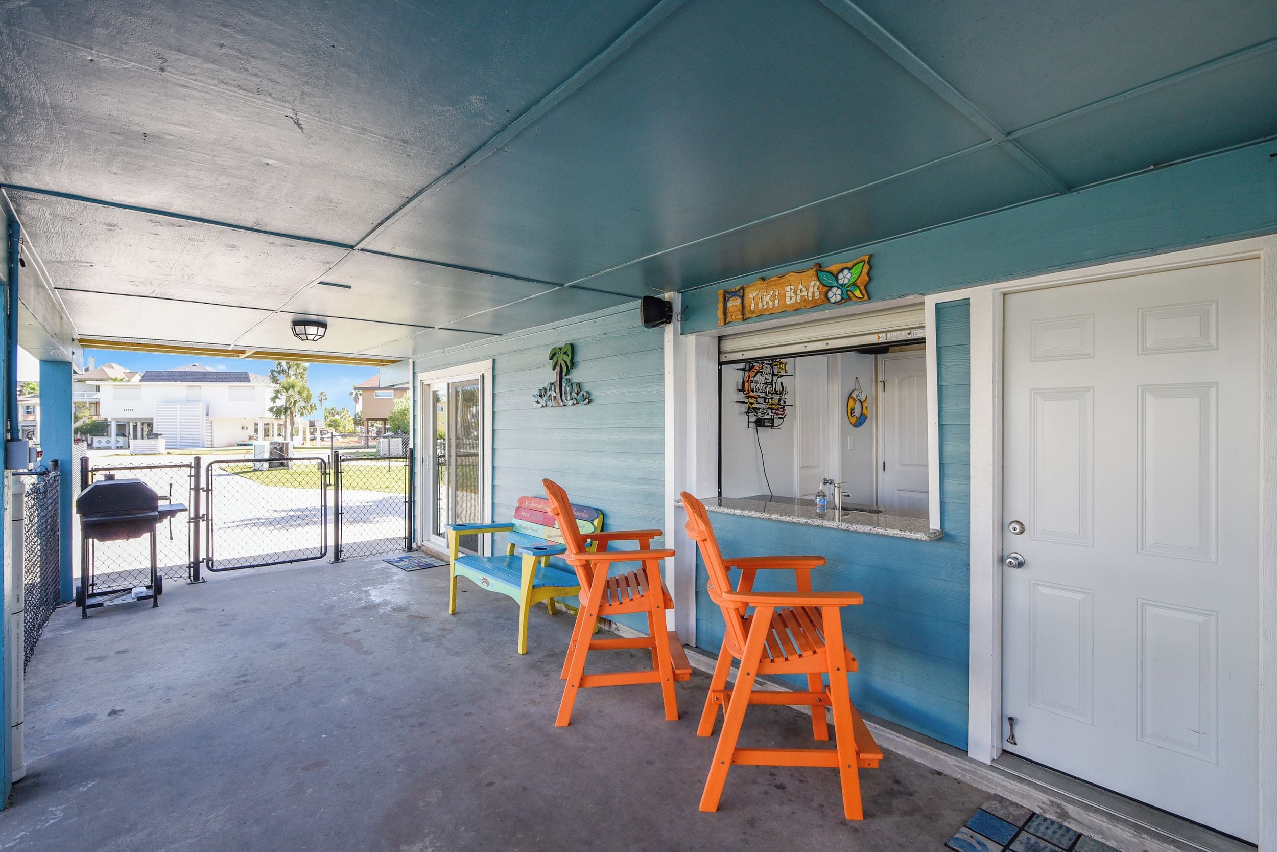 En tiki bar med udendørs siddepladser, grill og et skilt der siger "TIKI BAR".
