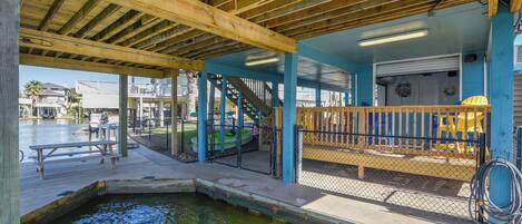 A covered outdoor area with a wooden deck, a small pool, and a staircase leading to a higher level.