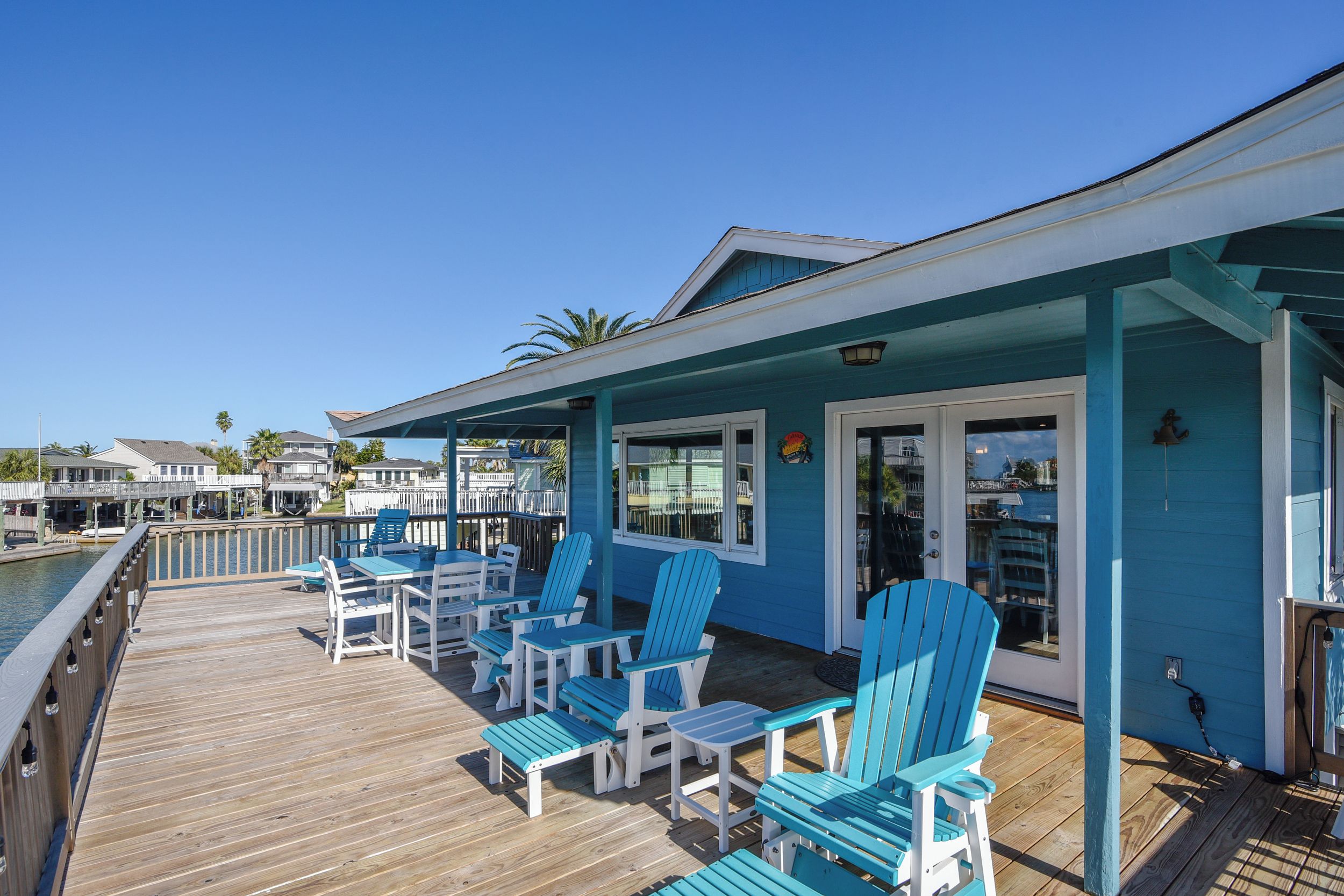 Eine Terrasse mit blauen Adirondack-Stühlen und einem Poolbereich.