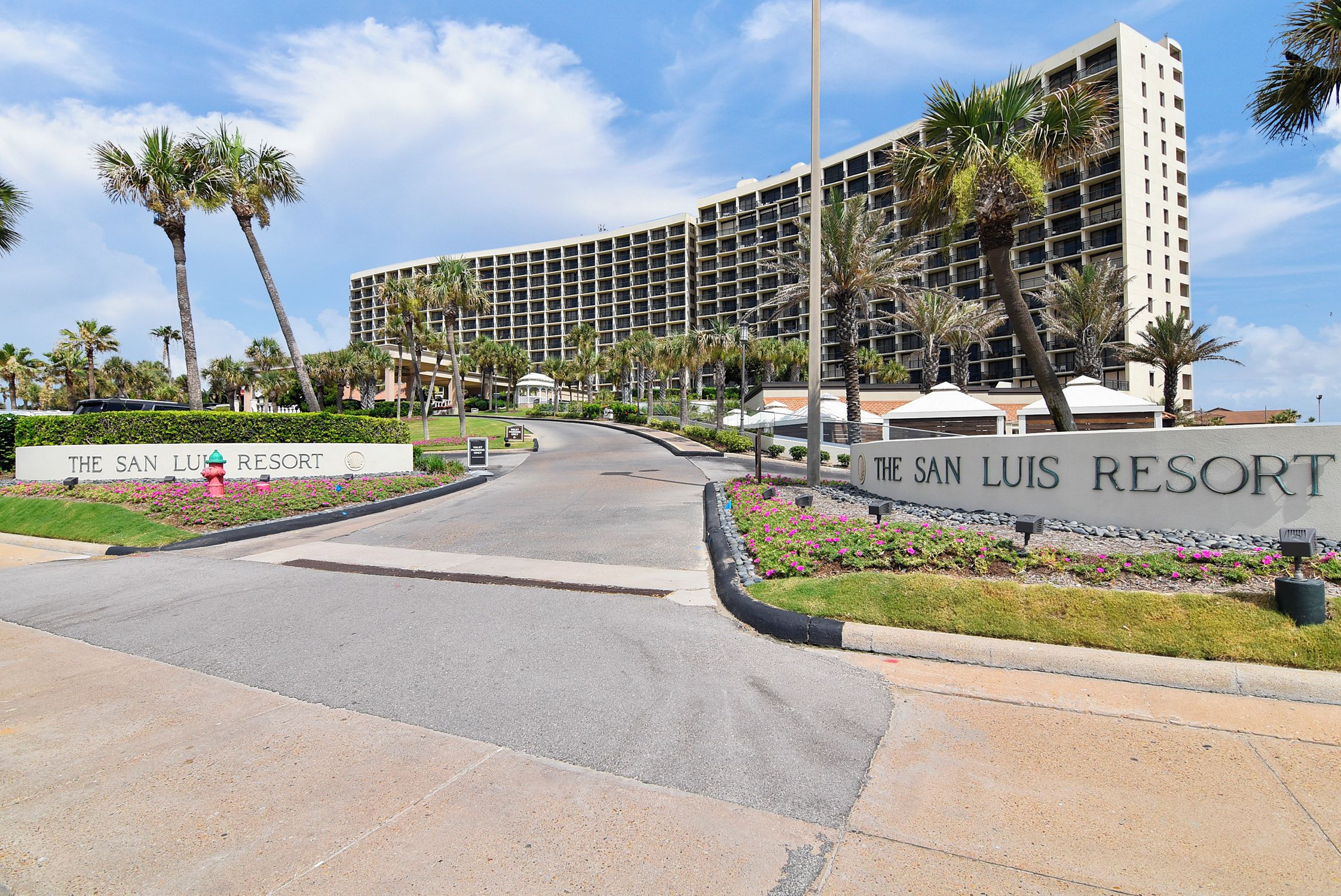 The San Luis Resort with a large building, palm trees, and a well-maintained entrance area.
