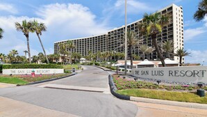 The San Luis Resort with a large building, palm trees, and a well-maintained entrance area. - Luis Landing by Ryson Vacation Rentals (Galveston)