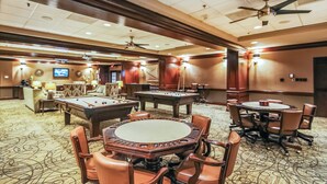 A hotel lobby with pool tables, comfortable seating, and a ceiling fan. - Luis Landing by Ryson Vacation Rentals (Galveston)
