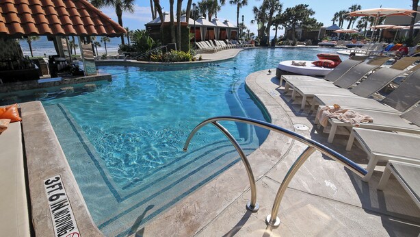 A pool area with lounge chairs, a bar, and a view of the ocean. - Luis Landing by Ryson Vacation Rentals (Galveston)