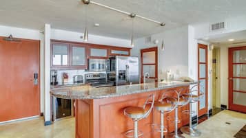Una cocina moderna con una isla central, electrodomésticos de acero inoxidable y una zona de bar con taburetes.