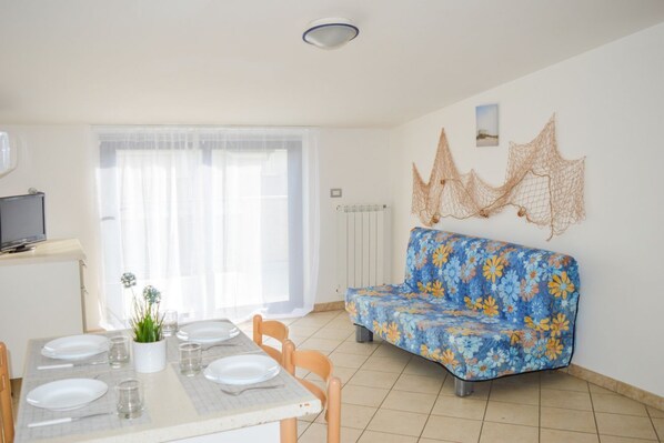 A dining area with a table set for four, a sofa, and a radiator on the wall.