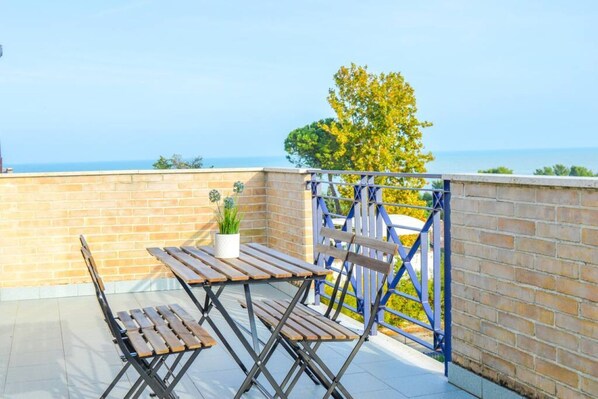A rooftop terrace with a wooden table and chairs, a potted plant, and a view of the sea. - Green Bay Village - B19 - Two-room apartment (Foggetta)