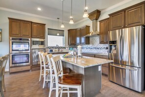 A modern kitchen with stainless steel appliances, wooden cabinets, and a central island with bar stools.