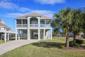 A two-story building with a covered front porch and a balcony. - Sandpiper Treasure by Ryson Vacation Rentals (Galveston)