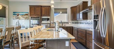 A modern kitchen with a central island, stainless steel appliances, and wooden cabinetry.