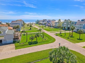A coastal residential area with houses, a clear sky, and a view of the ocean. - Sandpiper Treasure by Ryson Vacation Rentals (Galveston)