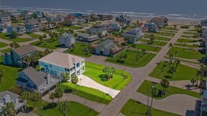 A coastal residential area with houses, a beach, and a clear sky. - Sandpiper Treasure by Ryson Vacation Rentals (Galveston)