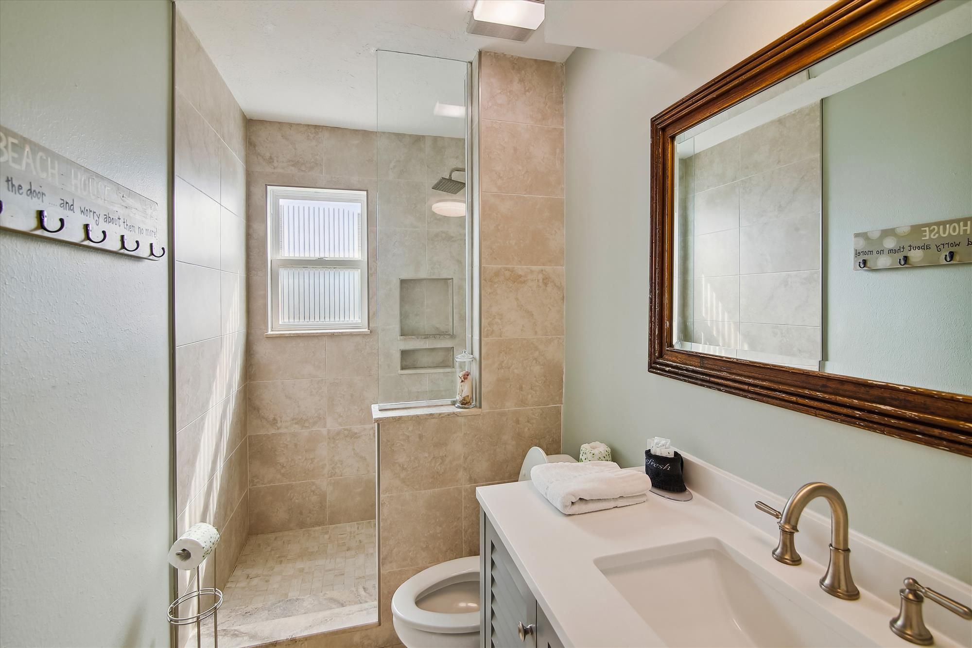 A bathroom with a glass shower enclosure, a toilet, a sink with a vanity, and a large mirror.