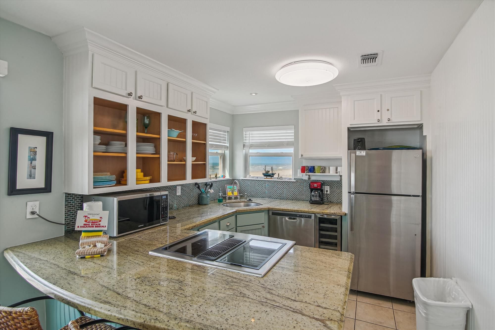 A modern kitchen with white cabinets, a stainless steel refrigerator, and a granite countertop.