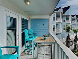 Enjoy the view from this balcony with a table and two chairs.
