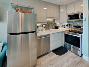 Fully equipped kitchen with refrigerator, dishwasher, oven, microwave, and toaster.