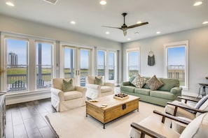 A spacious living room with large windows, a ceiling fan, and a view of a balcony.