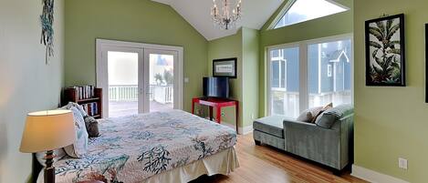 A bedroom with a bed, a desk, a chair, a lamp, and a balcony with a view.