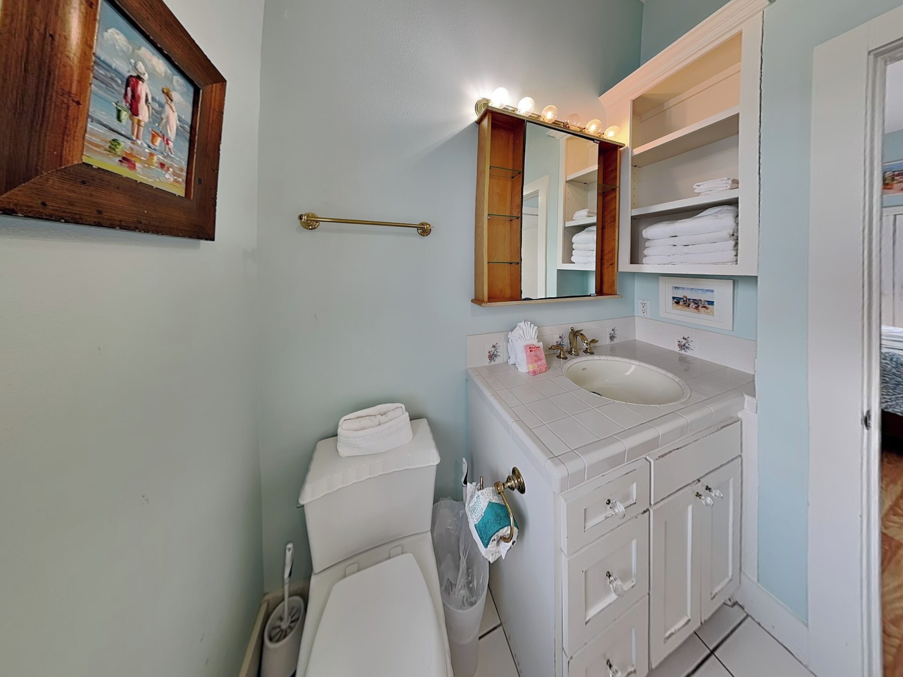 Un baño con inodoro, lavamanos, tocador y espejo con luces.