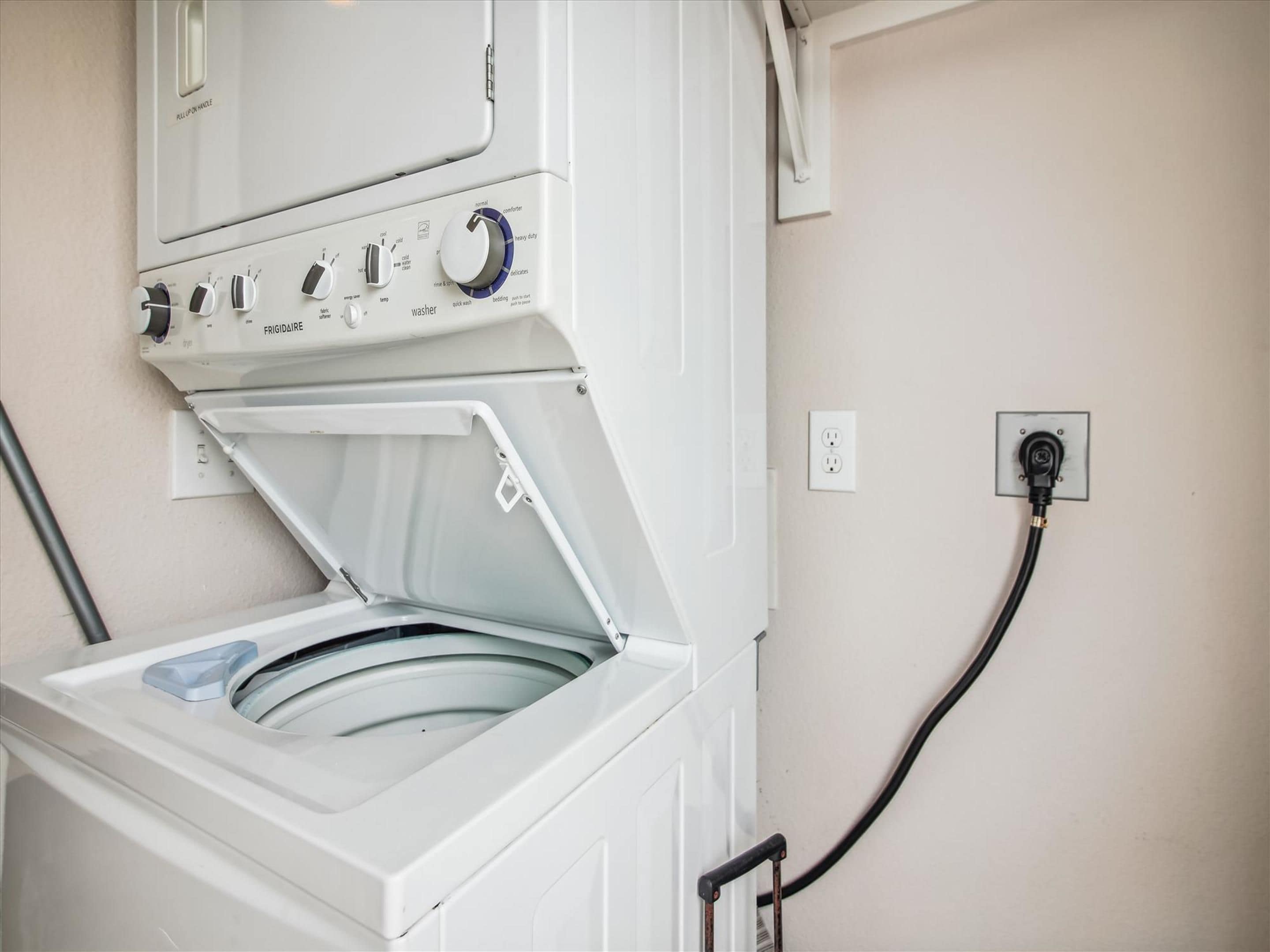 A front-loading washing machine with a control panel, a power outlet, and a power cord.
