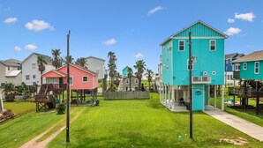Un barrio residencial con casas coloridas, un jardín con césped y un cielo azul despejado.