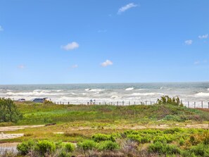 Un paysage côtier avec vue sur l’océan, une zone herbeuse et une clôture.