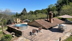 Una azotea con piscina, mobiliario exterior y chimenea de piedra.