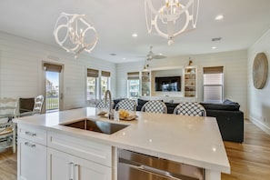 A spacious kitchen with a large island, white cabinetry, and a built-in dishwasher. - The Conch Castle by Ryson Vacation Rentals (Galveston)
